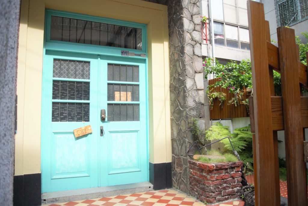 「同・居 With Inn Hostel」のエメラルドグリーンに塗られたドア